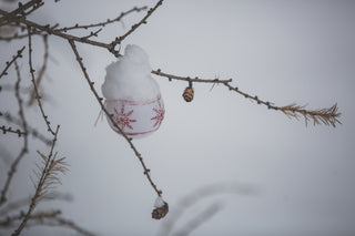 Red Christmas ornament resting on fresh snow with festive decorations and winter vibes