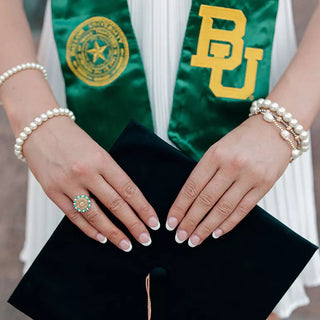 Customer showing off her Baylor Class Ring while holding her graduation hat | Picture taken at Baylor University Graduation