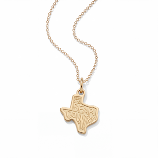 A gold necklace with a pendant shaped like the state of Texas, featuring the engraved text 'MAKE YOUR BEAR COUNTRY' on a clean white background.