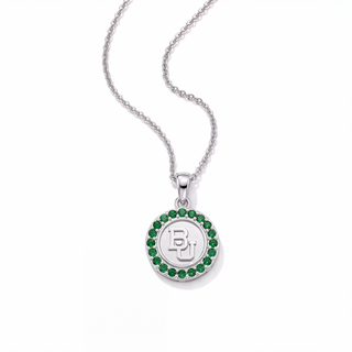 A silver pendant necklace featuring a circular charm with a green gemstone border and a central silver monogram logo, displayed on a clean white background.