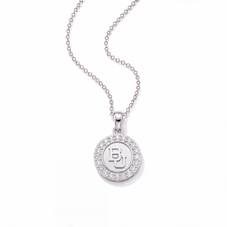 A silver round pendant necklace featuring a halo of small clear stones and a central monogram logo, suspended from a delicate silver ball chain on a white background.