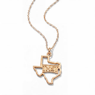 A  gold necklace featuring a pendant shaped like the state of Texas, with the letters 'TXST' cut out in the center, suspended from a delicate cable chain on a white background.