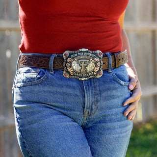Person wearing blue jeans with a Texas Tech University belt buckle.