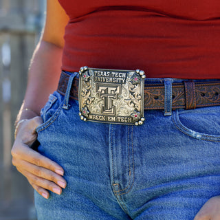 Person wearing a Texas Tech University belt buckle on blue jeans 