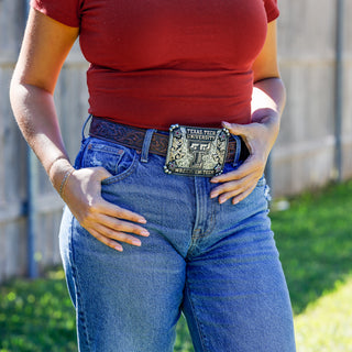 Person wearing a red shirt and blue jeans with a Texas Tech University belt buckle.