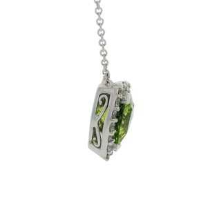 Green peridot pendant on a chain against a white background showing filigree style cutout
